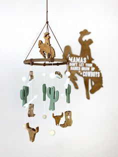 "This classic western baby crib mobile is one of my favorite designs to date. I love the vintage cowboy vibes and I'm sure you and your little rodeo baby will too! It has a cowboy riding a horse, two cowboy boots, two cowboy hats, two cattle skulls, four cacti, four accent arrows, four white wool pom balls and four tan wool pom balls. The wood tones paired with a neutral color palette and traditional brown (faux) leather make this piece both charming and rustic. The pieces are cut from pine, sta Rodeo Nursery, Vintage Cowboy Nursery, Western Crib, Western Baby Nurseries, Cowboy Vibes, Rodeo Baby