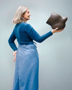 a woman in a blue dress is holding a hat