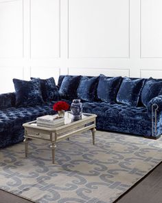 a living room filled with blue couches and pillows on top of a gray rug