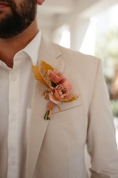 a man in a white suit with a boutonniere on his lapel