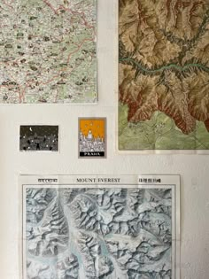 several maps are hanging on the wall in front of each other, including mountains and valleys