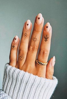 a woman's hand with tattoos on her fingers and two fingers in the shape of hearts