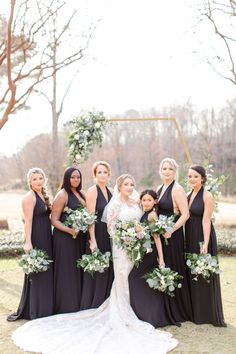 the bride and her bridesmaids pose for a photo in front of an arch decorated with greenery