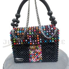 This one-of-a-kind, finely assembled, marble pattern bead by bead black and a multicolor bag is designed in a fold-over silhouette with two different straps (chain and wooden beaded nylon rope strap) and a magnetic snap that opens to reveal room for all your essentials. * Black and multicolor round beads * Marble pattern beads * Gold-tone hardware * Magnetic snap closure * Flap style * Unlined * Detachable straps * Shoulder length chain strap * Wooden beaded nylon rope strap * 8.5"W X 6"H X 3"D Trendy Multicolor Beaded Bags, Trendy Multicolor Beaded Shoulder Bag, Elegant Multicolor Beaded Square Shoulder Bag, Trendy Multicolor Shoulder Bag For Evening, Elegant Multicolor Square Beaded Shoulder Bag, Black Beaded Square Shoulder Bag, Multicolor Beaded Crossbody Shoulder Bag, Black Beaded Shoulder Bag, Black Beaded Rectangular Shoulder Bag