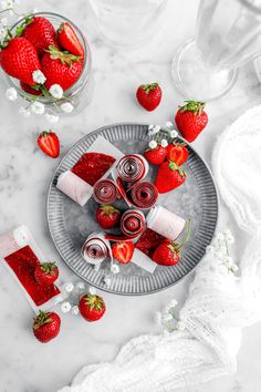 strawberries and whipped cream on a plate next to some glass containers with strawberries