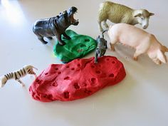 four toy animals on top of a white table next to some rocks and zebras