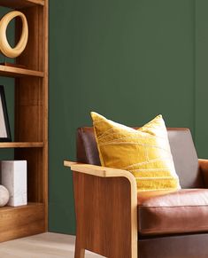 a brown leather chair sitting in front of a green wall