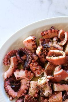 an octopus and squid dish in a white bowl