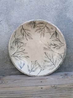 a white plate sitting on top of a wooden table next to a gray cement wall