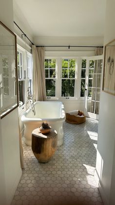 a bathroom with an oval bathtub and two wooden stools in front of the tub