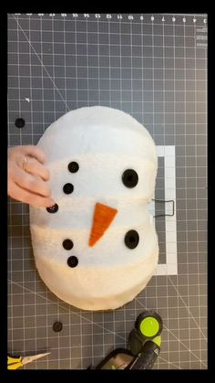 someone making a snowman out of toilet paper on top of a cutting board with scissors