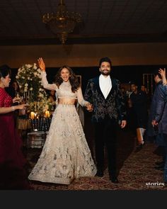 a man and woman are walking down the aisle at their wedding reception with guests in the background