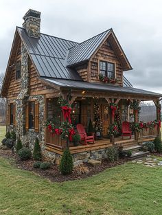 a log cabin with red chairs and wreaths on the front porch is decorated for christmas