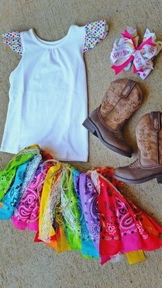 a white shirt, cowboy boots, and colorful skirt are laid out on the floor