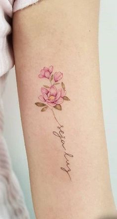 a woman's arm with pink flowers on it and the word love written in cursive writing