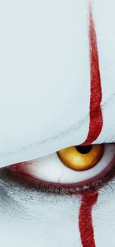 the eye of a demonic looking person with red streaks on it's left side