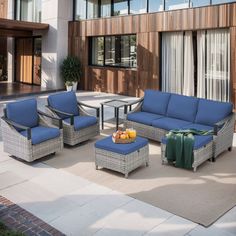 an outdoor patio with blue cushions and wicker furniture on the ground near a building