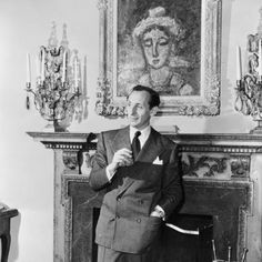 a man in a suit and tie standing next to a fireplace