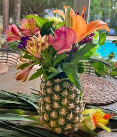 a pineapple vase filled with colorful flowers on top of a table next to a pool