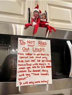 two elfs sitting on top of an oven with a sign attached to it that says don't read out loud