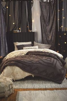 a bed with brown and white comforter in a bedroom next to curtains on the wall