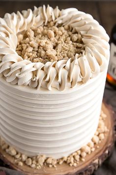 a close up of a cake with icing on a wooden table next to a bottle