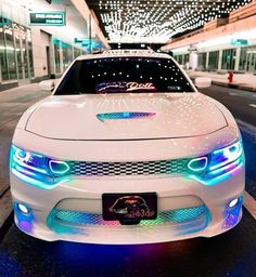 a white car with blue lights on it's hood parked in front of a building