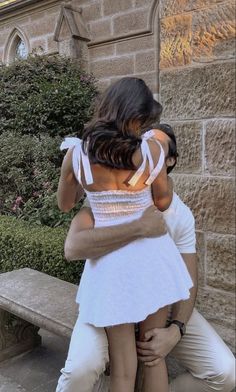 a man and woman hug each other in front of a bench