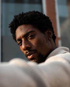 a close up of a person wearing a sweater and looking off to the side with a serious look on his face