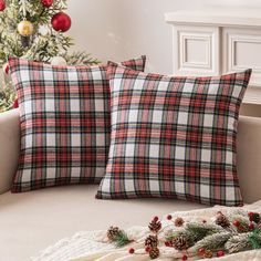 two plaid pillows sitting on top of a couch next to a christmas tree