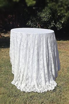 a white table cloth on top of a round table in the middle of a field