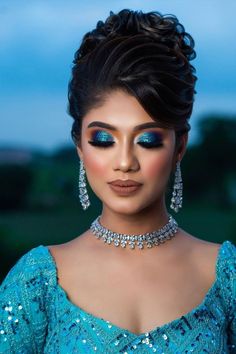 a woman with blue makeup and jewelry on her face, posing for a photo in the evening