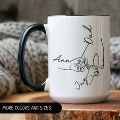 a black and white coffee mug sitting on top of a wooden table next to a blanket