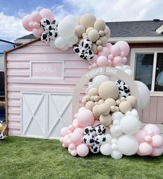 a bunch of balloons are in front of a pink building with a cow on it