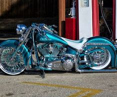 a shiny blue motorcycle parked in front of a gas station with no one around it