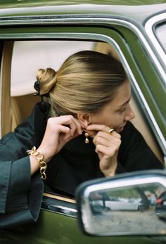 a woman sitting in the back seat of a car with her hand on her ear