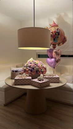 a table topped with lots of gifts under a light fixture next to a lamp shade