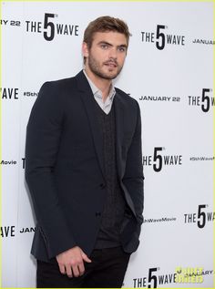 a man standing in front of a white wall with the number five on it's side