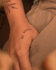 a person with a small tattoo on their wrist that says be brave in black ink