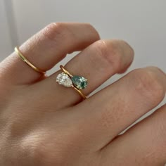 a woman's hand with a gold ring and two stone rings on her fingers