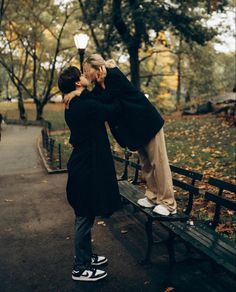 two people are kissing on a park bench