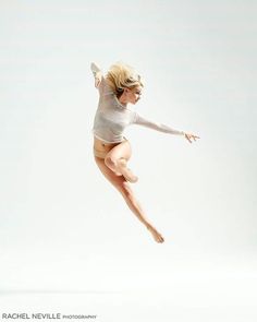 a woman is jumping in the air with her legs spread out and one leg up