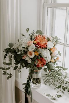 a vase filled with flowers sitting on top of a white table next to a window