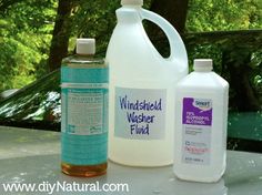 two bottles of wash and one bottle of liquid are sitting on a white table with trees in the background