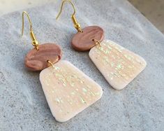 two wooden earrings with white and brown designs on them sitting on a piece of paper