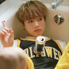 a young boy sitting in a bathtub holding up his peace sign