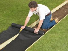 a man laying on top of a black tarp in the middle of a field