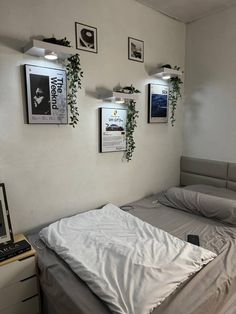 an unmade bed in a room with pictures on the wall