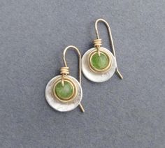 Faceted green genuine peridot gemstones, weighing 1.25 carats each, are wrapped in gold filled wire, then set within a sterling disc dangle. Ear hooks are handcrafted in gold filled wire. Artisan elegance and lightweight design make these earrings perfect for all day wear and comfort. Also are a great gift for a special someone with an August birthday, as peridot is August's birthstone. Genuine peridot, 1.25 carats each (2.5 carats per pair), pale green with natural inclusions visible. Earring D Elegant Green Hammered Earrings, Teardrop Peridot Jewelry For Anniversary, Green Peridot Drop Earrings, Peridot Dangle Earrings For May Birthstone, Green Peridot Earrings For Anniversary, Green Sterling Silver Hammered Jewelry, Green Hammered Sterling Silver Jewelry, Lime Green Jewelry With Matching Earrings For Gift, Nickel Free Peridot Jewelry