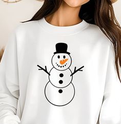 a woman wearing a white snowman sweatshirt with an orange nose and black hat on her head